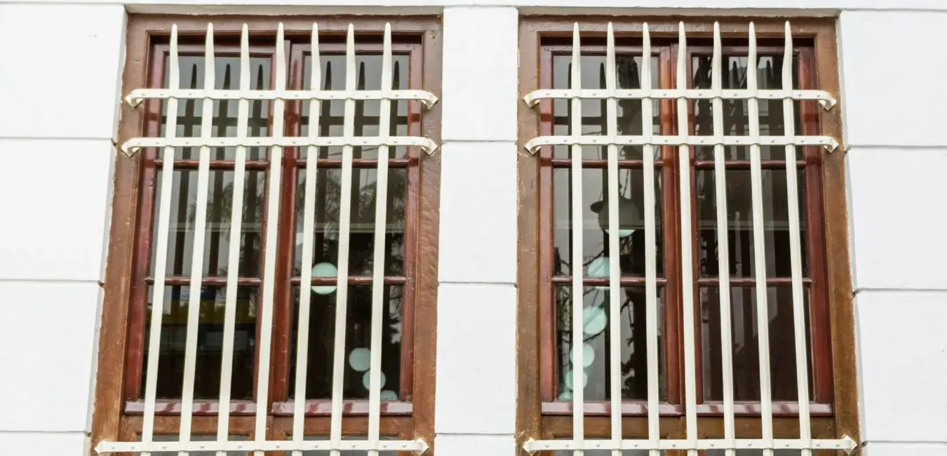 White steel burglar bars fitted over two wooden windows