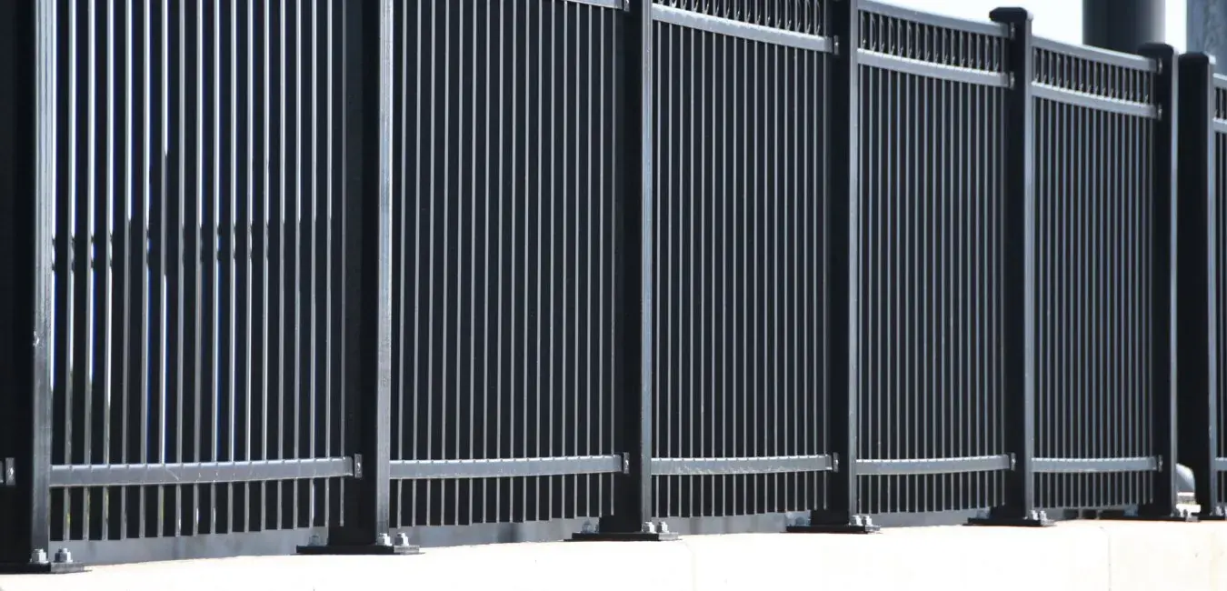 Black steel security fencing panels bolted to a concrete base